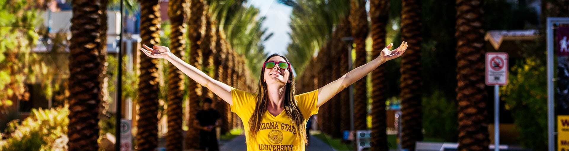 student with arms open on palm walk