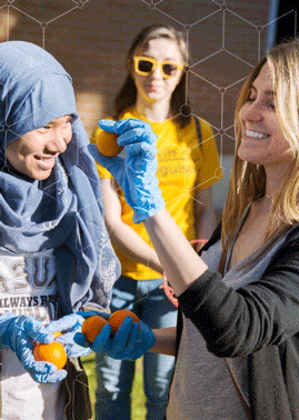 image of a student showing another student a orange