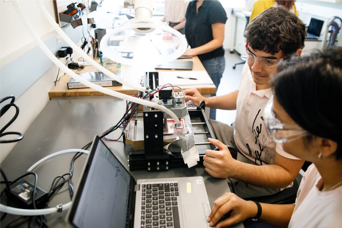 A group of people trying to build a project using tools and a laptop are in a lab
