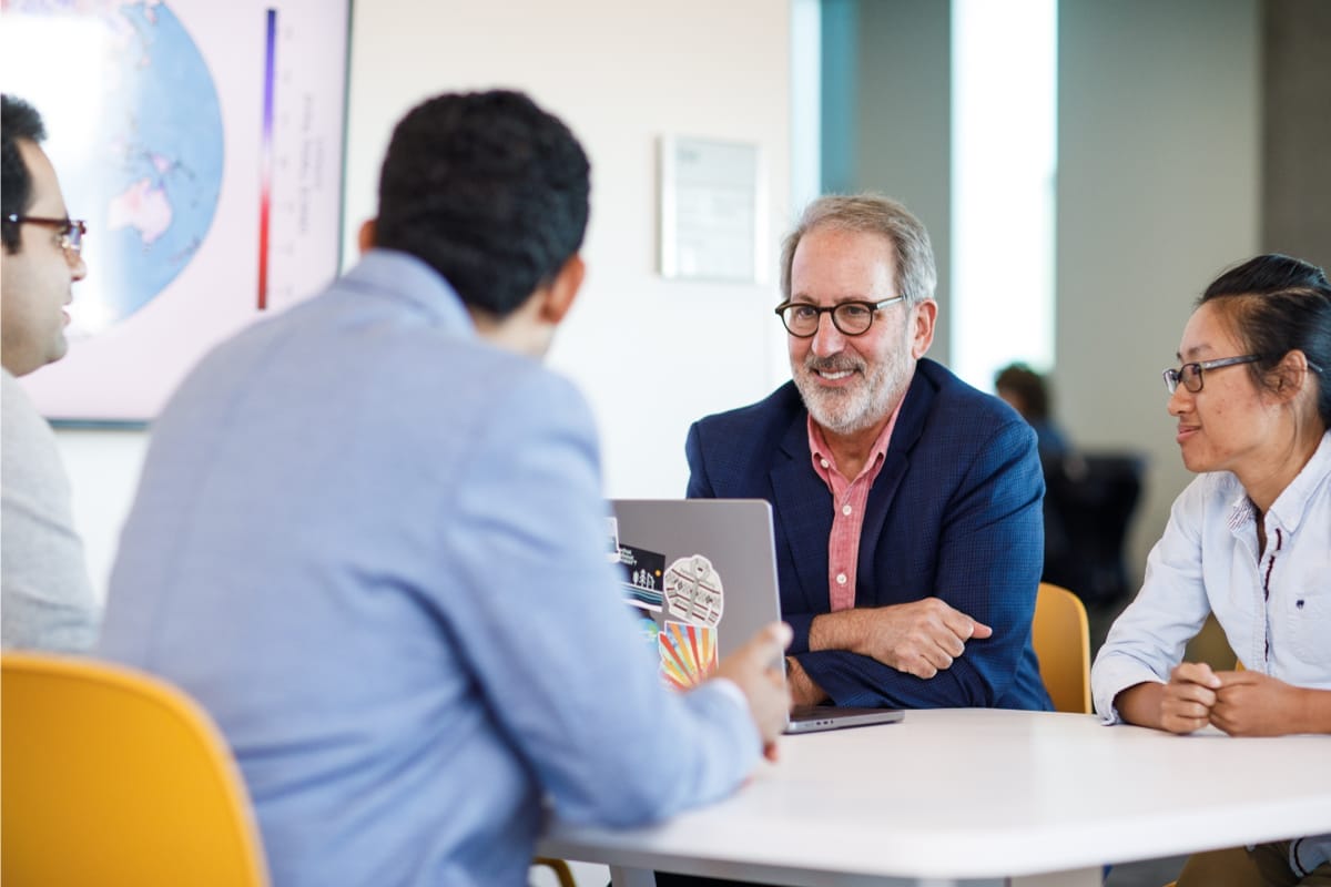 A group of people are talking to each other while sitting around a table and wearing professional clothes