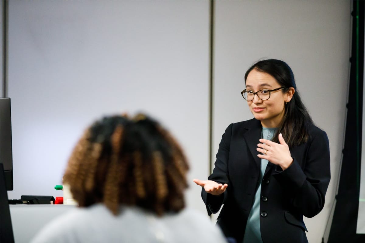 One person is standing and talking to someone who is sitting on the chair